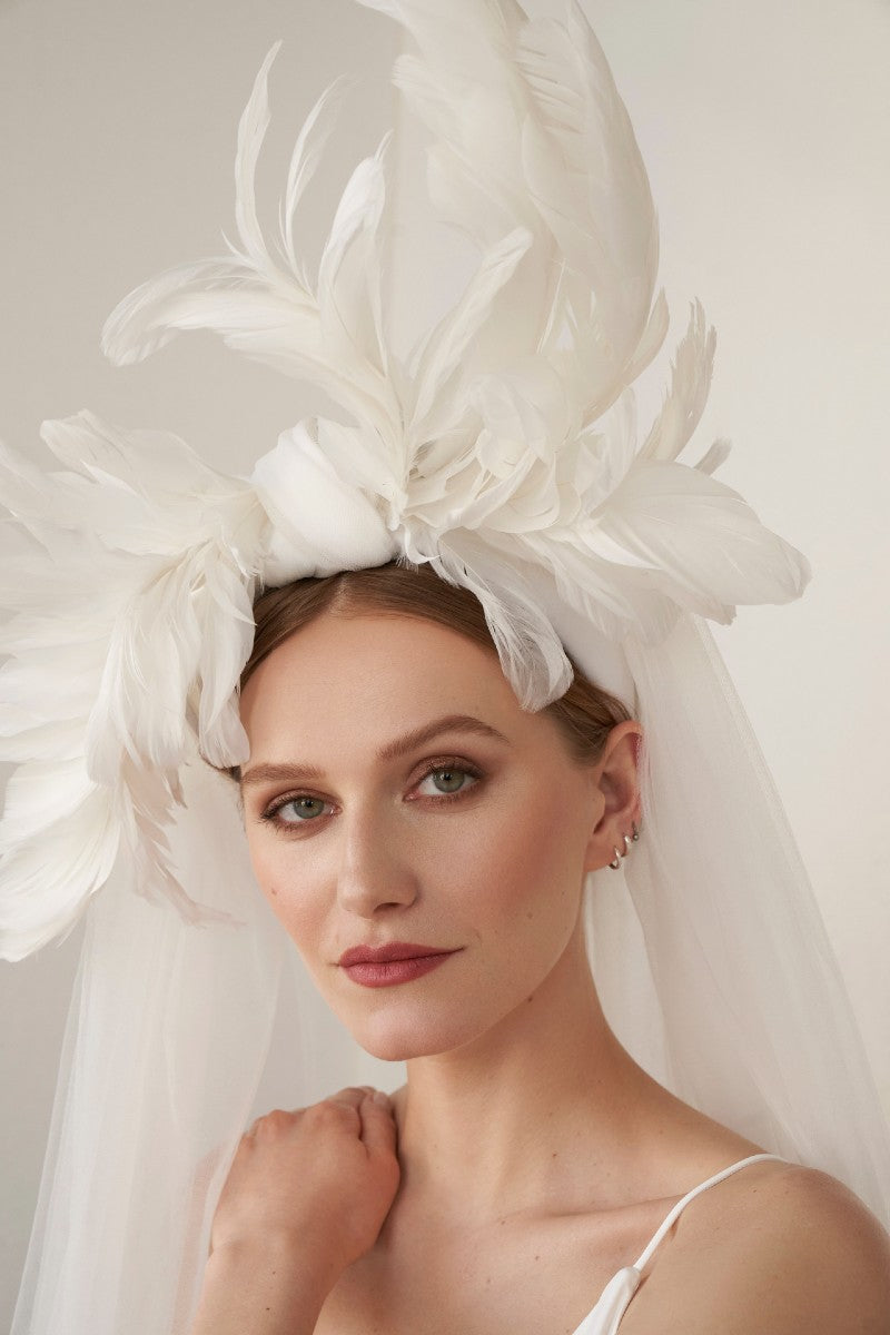 Woman wearing a feather bridal headpiece with veil