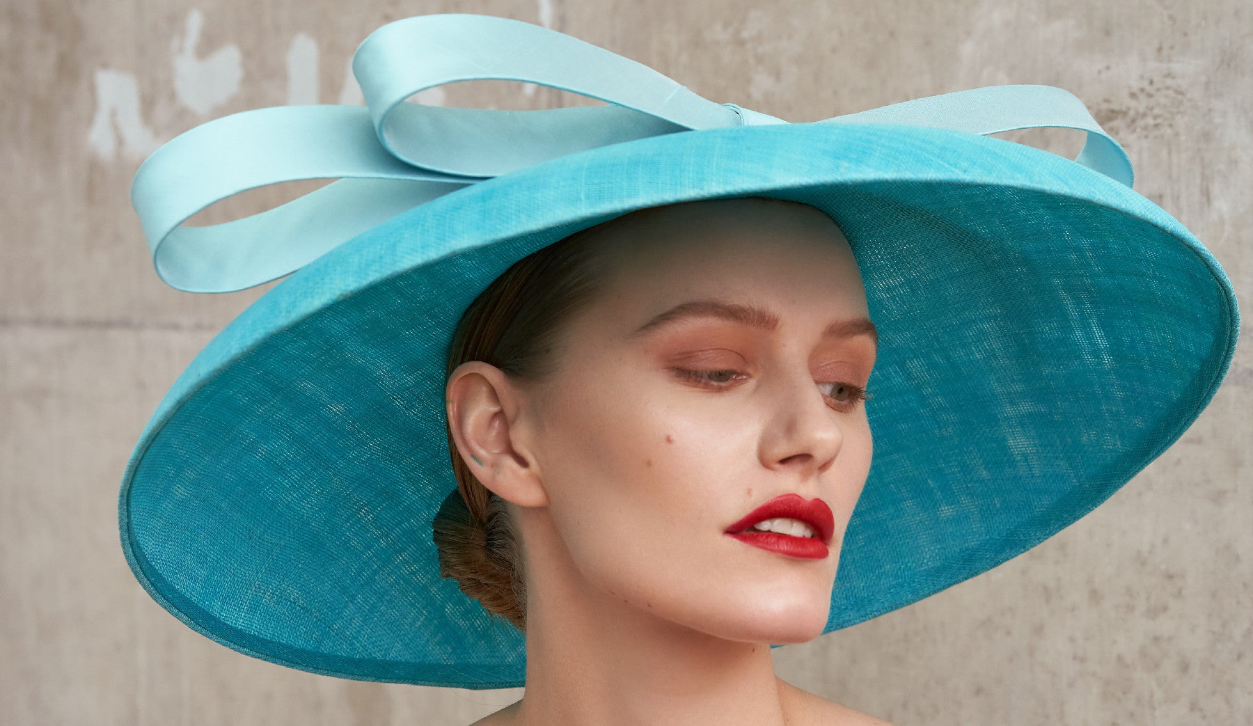 Woman wearing a wide brim turquoise blue sinamay hat with big bow