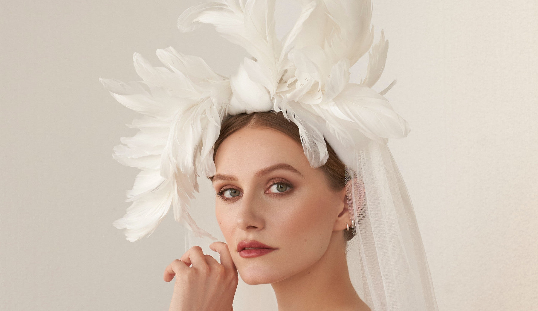 Woman wearing a feather bridal headpiece with veil